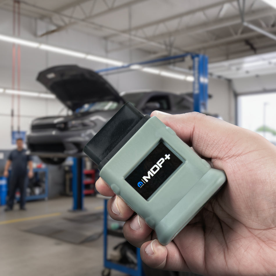 MDP+ In a mechanic shop where a dodge charger is suspended on a lift.