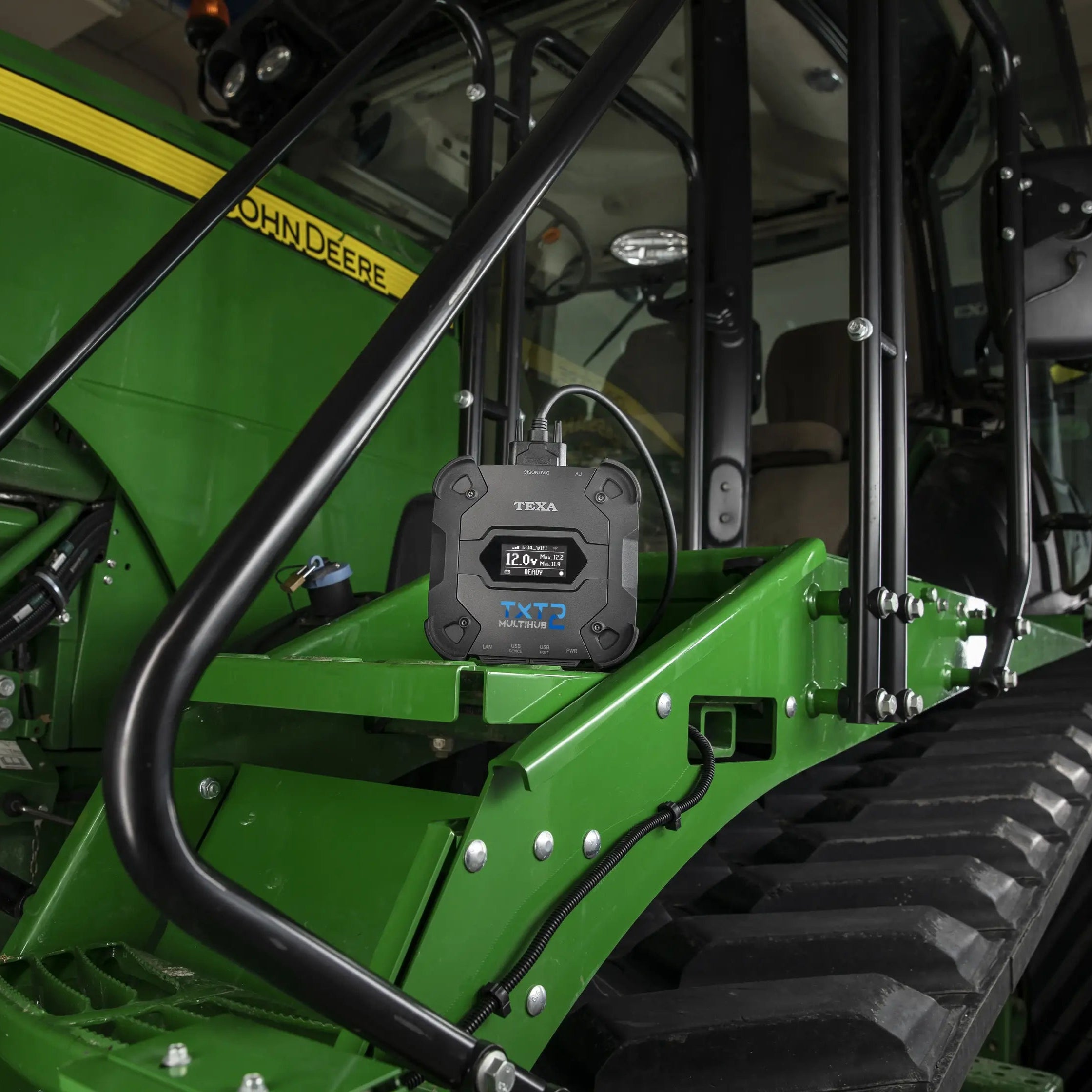 Close-up of a green John Deere tractor with a TXT 2 attached to it.