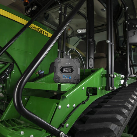 Close-up of a green John Deere tractor with a TXT 2 attached to it.