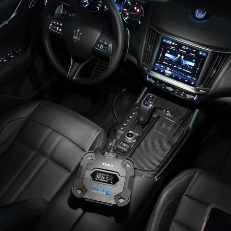 Car interior with dashboard, steering wheel, and gear shift in dark lighting with the TEXA TXT MULTIHUB 2 sitting on the center console.